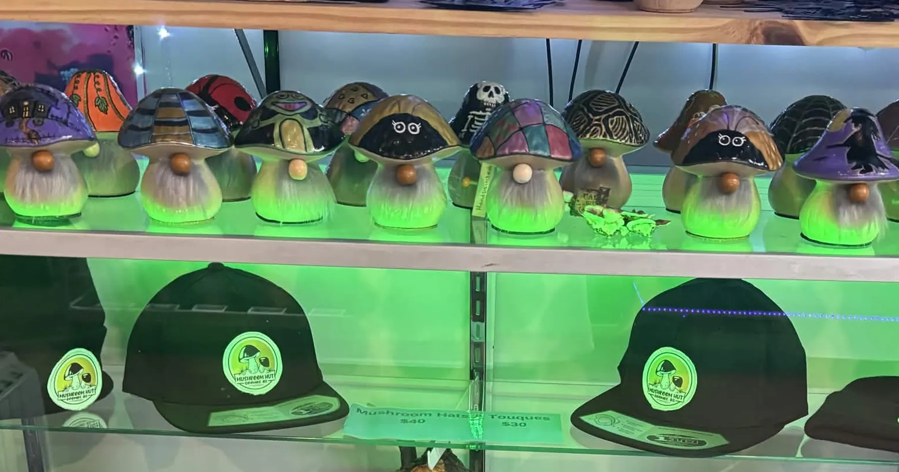 Colourful mushroom gnomes and Mushroom Hut hats in the shop's display case